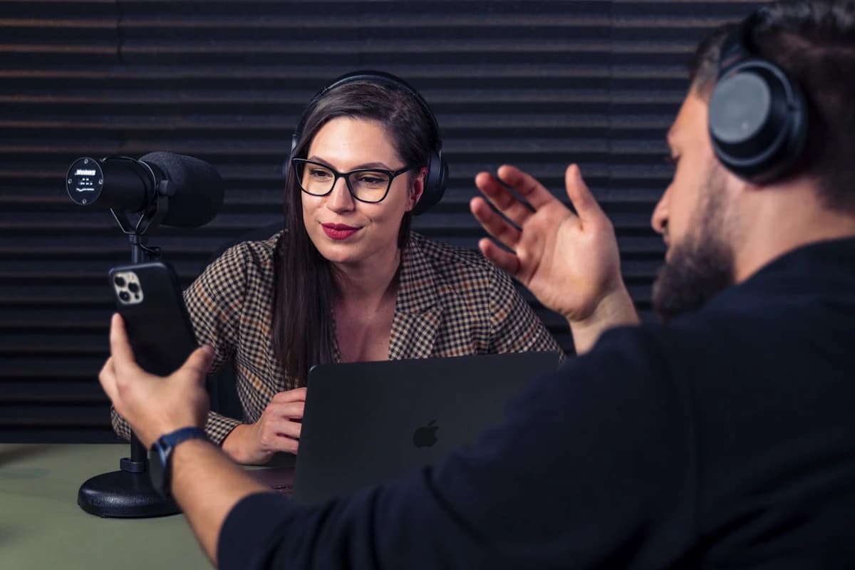 Podcast studio desk with microphones and a music bed on screen